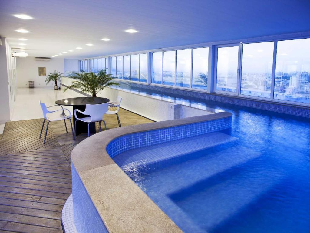 a swimming pool with a table and chairs in a building at Plaza São Rafael Hotel in Porto Alegre