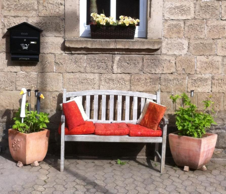 un banco con almohadas rojas y naranjas frente a un edificio en The Cozy Cottage, en Rieden