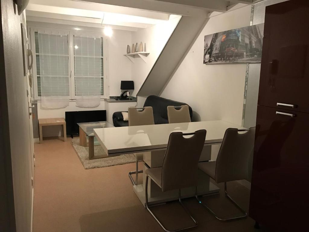 Una sala de estar con una mesa y sillas blancas. en Appartement Rue Victor Hugo - Port de la Houle, en Cancale