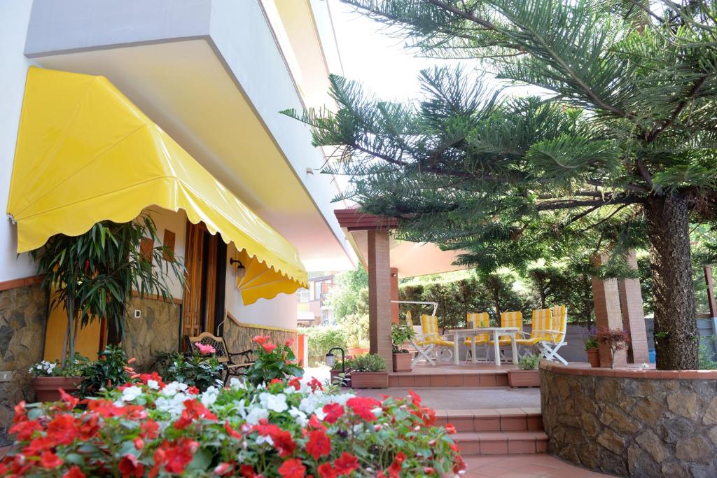 un patio con una sombrilla amarilla y algunas flores en Villa Eden, en Corbara