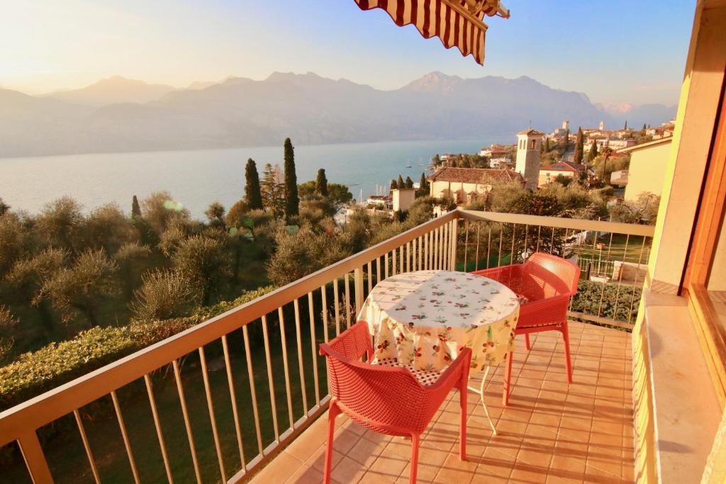 balcón con mesa, sillas y vistas al agua en Apartament Magnific Lake View, en Malcesine