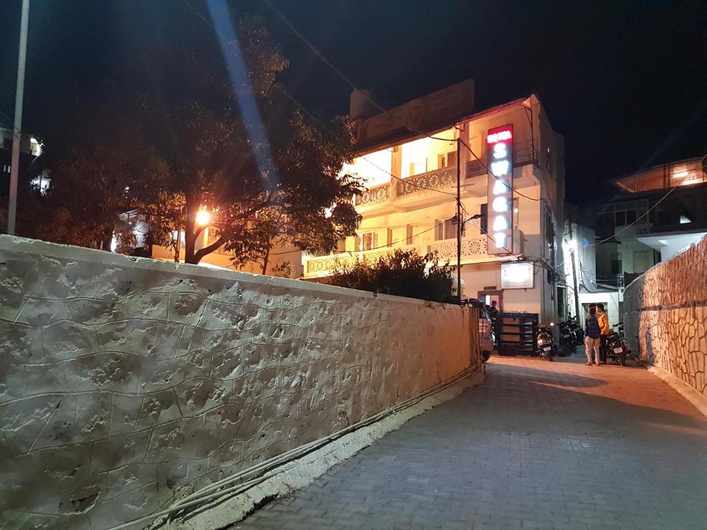 a street at night with a wall and a building at Hotel Swagat in Mount Ābu