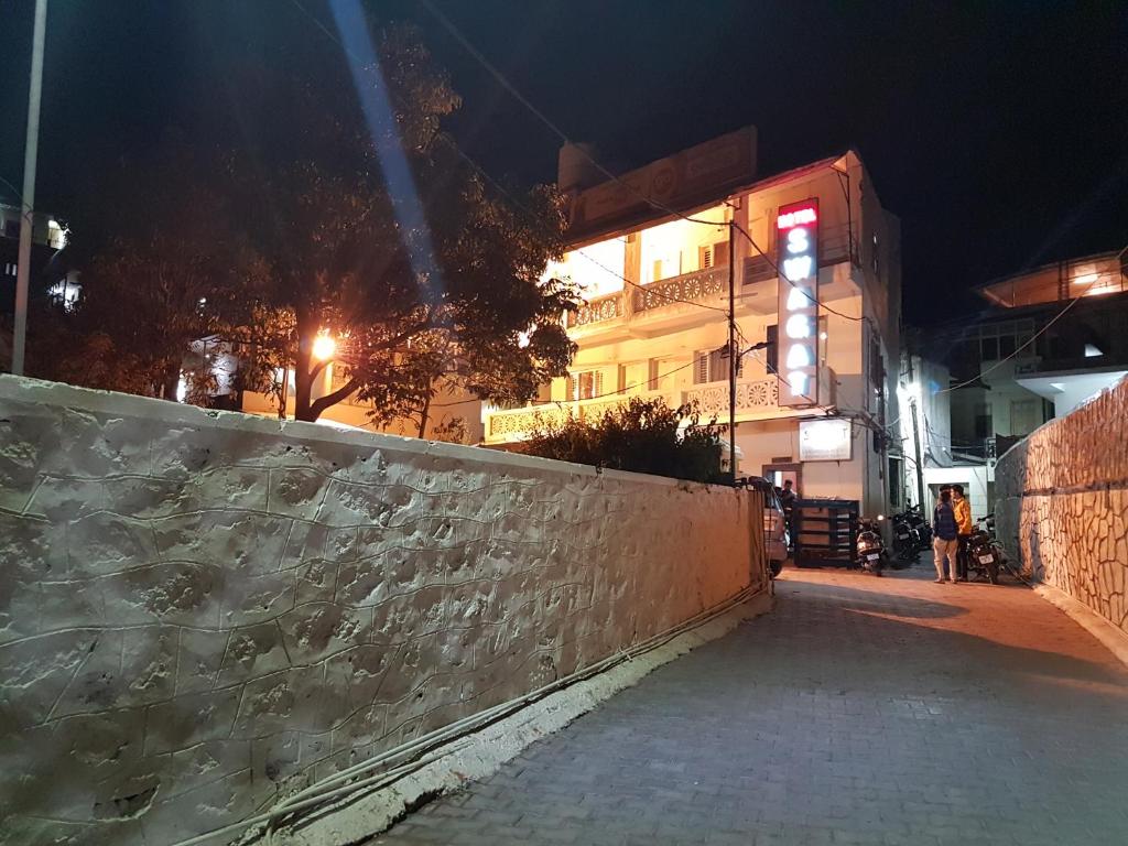 een straat 's nachts met een muur en een gebouw bij Hotel Swagat in Mount Ābu