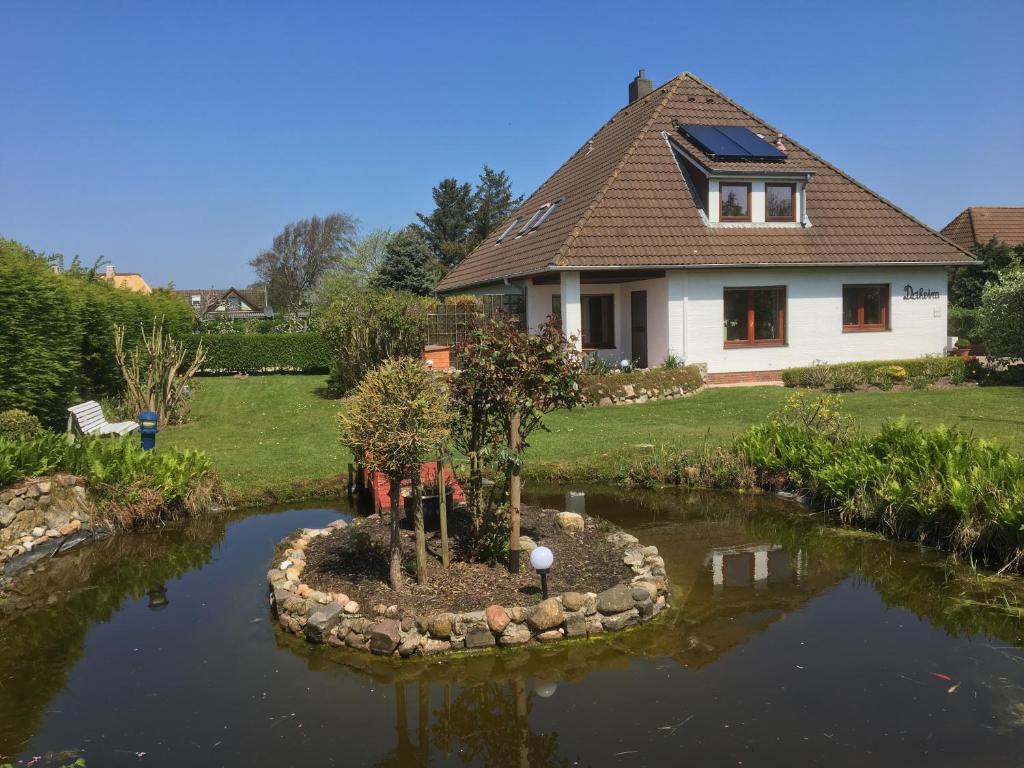 a house with a tree in the middle of a pond at Haus Daheim in Utersum