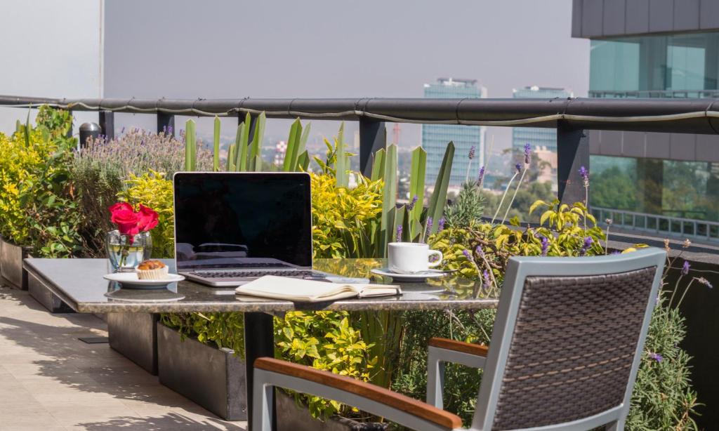 An outdoor work table with a laptop overlooking planted terrace space.