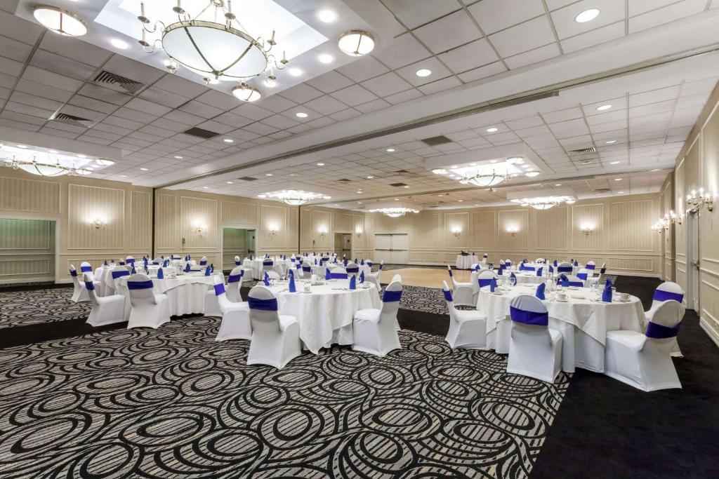 a banquet hall with white tables and chairs and a chandelier at Wyndham Southbury in Southbury