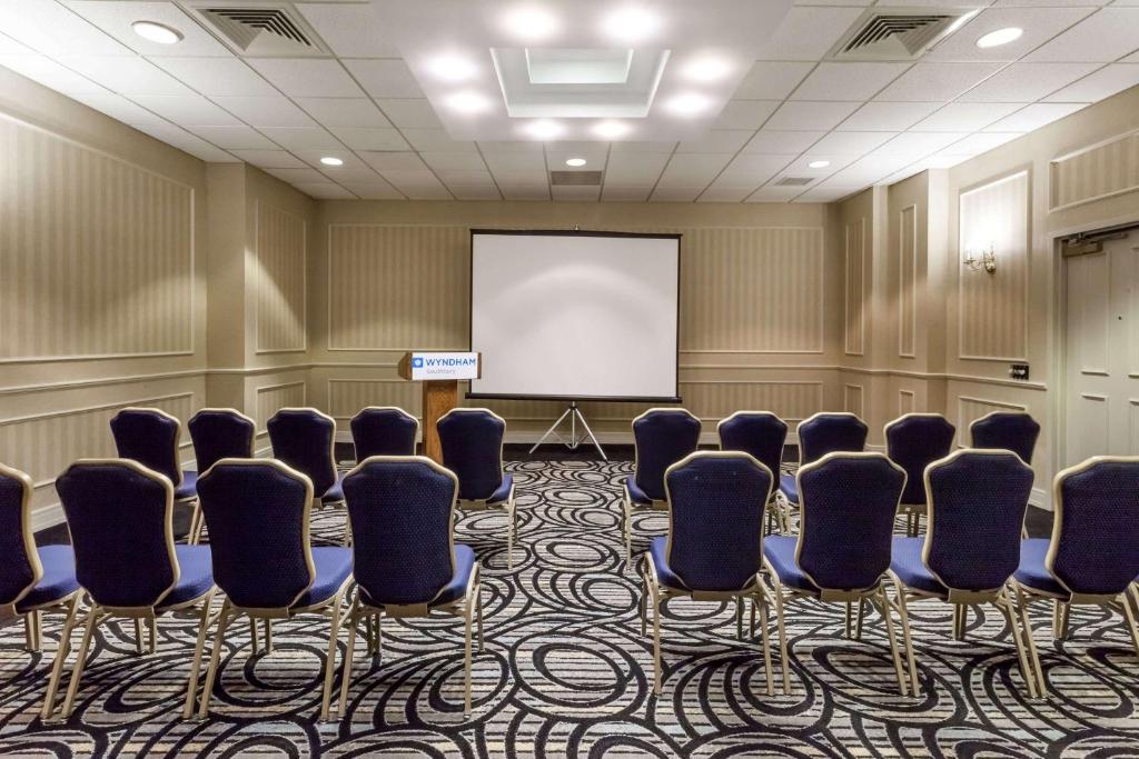 a conference room with chairs and a white screen at Wyndham Southbury in Southbury