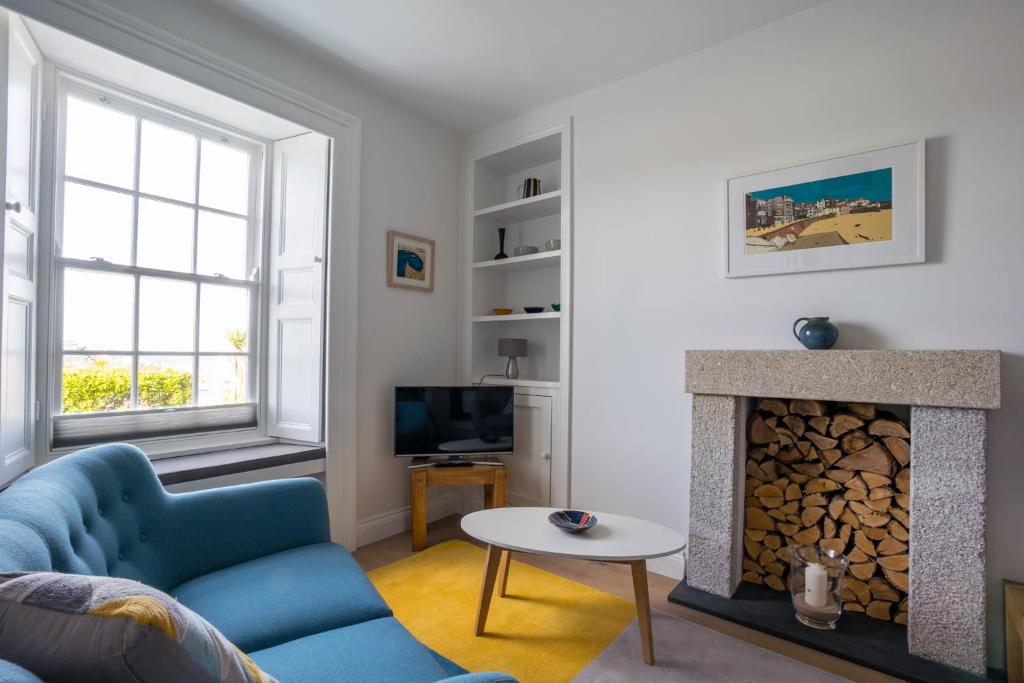 a living room with a blue couch and a fireplace at Tregenna Apartments in St Ives