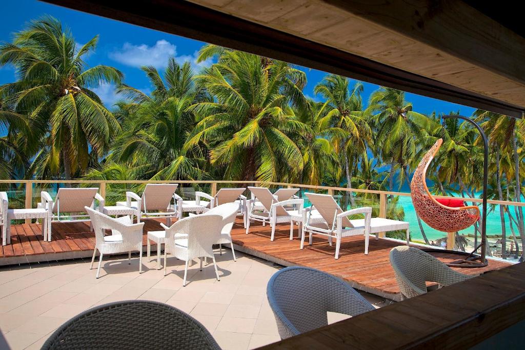 a patio with chairs and tables and the ocean at Kaani Beach Hotel in Maafushi
