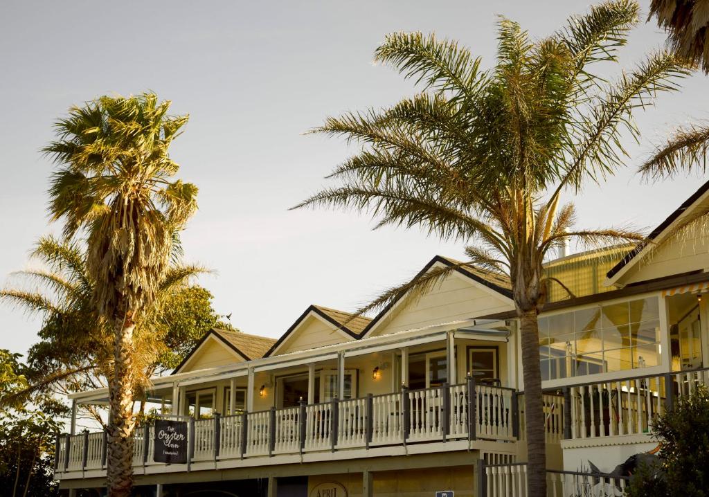 a house with palm trees in front of it at The Oyster Inn in Oneroa