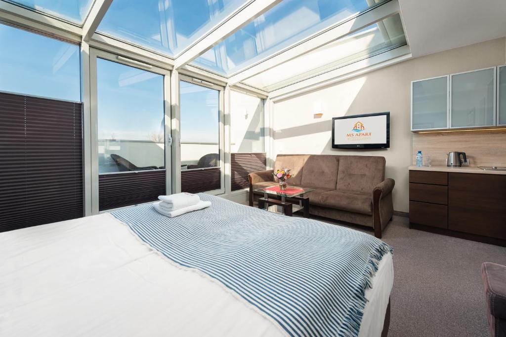 une chambre avec un lit, un canapé et des fenêtres dans l'établissement MS Apart Władysławowo, à Władysławowo