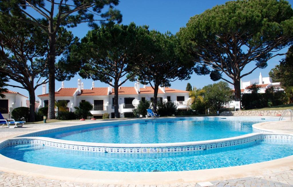 uma piscina em frente a uma casa com árvores em 3 Bed Holiday Home Lakeside Village Quinta Do Lago em Faro