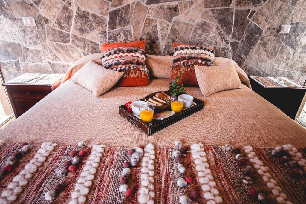 a bed with a tray of food on it at Lodge Quelana in San Pedro de Atacama