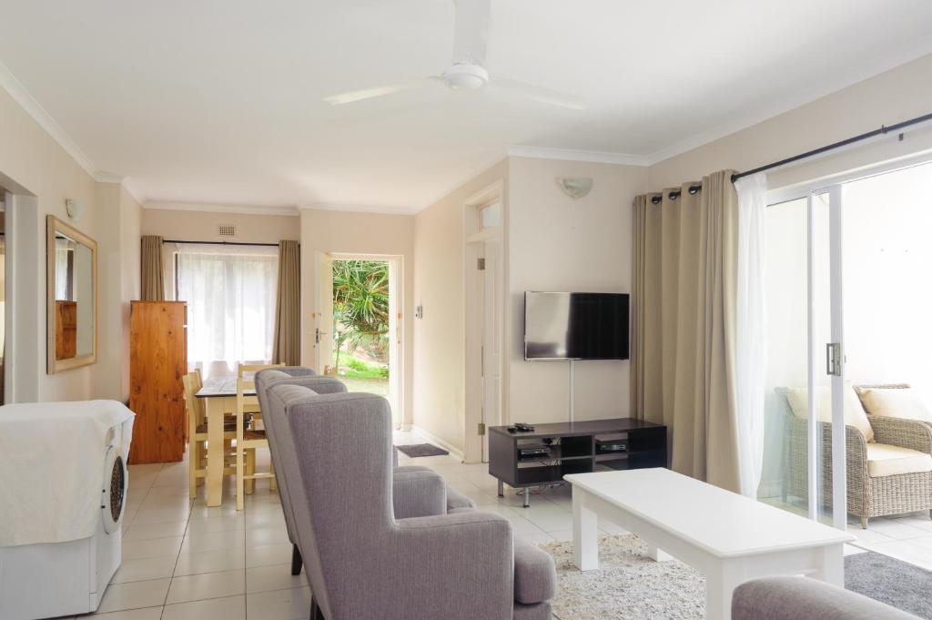 uma sala de estar com cadeiras, uma mesa e uma televisão em Martinique 44 em Ballito