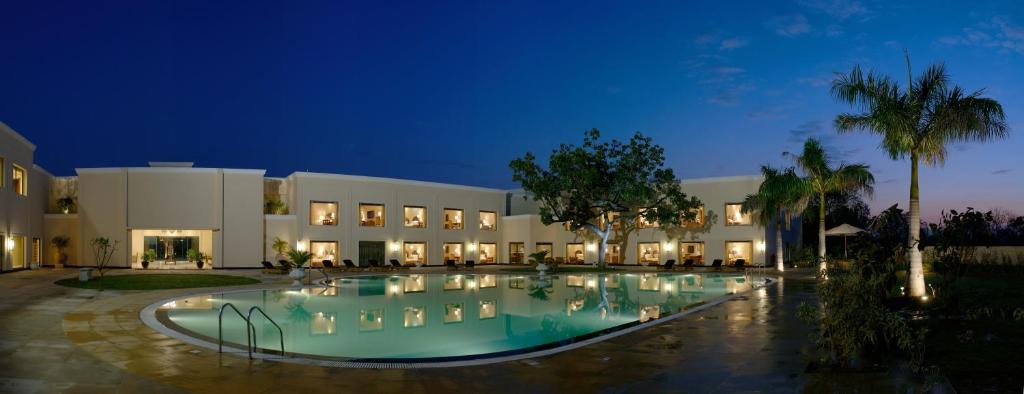 a large building with a swimming pool at night at The Lalit Traveller Khajuraho in Khajurāho