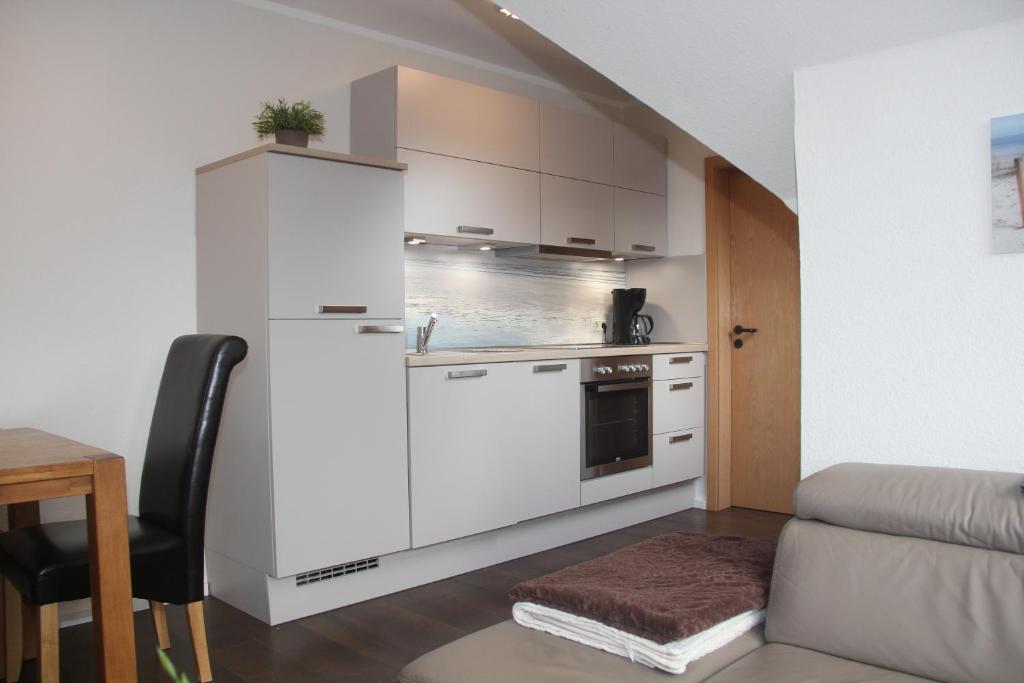 a kitchen with white cabinets and a table and a chair at Padua W05 in Cuxhaven