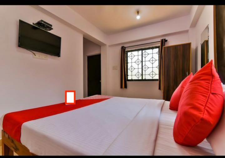una camera da letto con un grande letto bianco con cuscini rossi di Sweet AC Rooms near KFC Restaurant a Saligao
