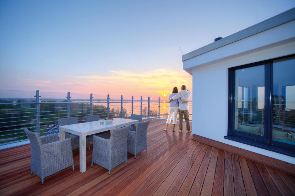 two people standing on a balcony with a table and chairs at Penthouse Müritzblick in Rechlin