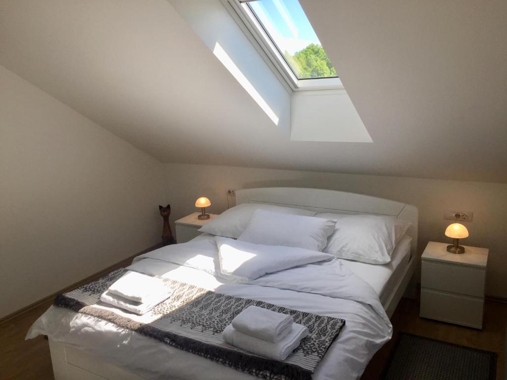 1 dormitorio con 1 cama con sábanas blancas y tragaluz en Rooms Garden, en Slunj
