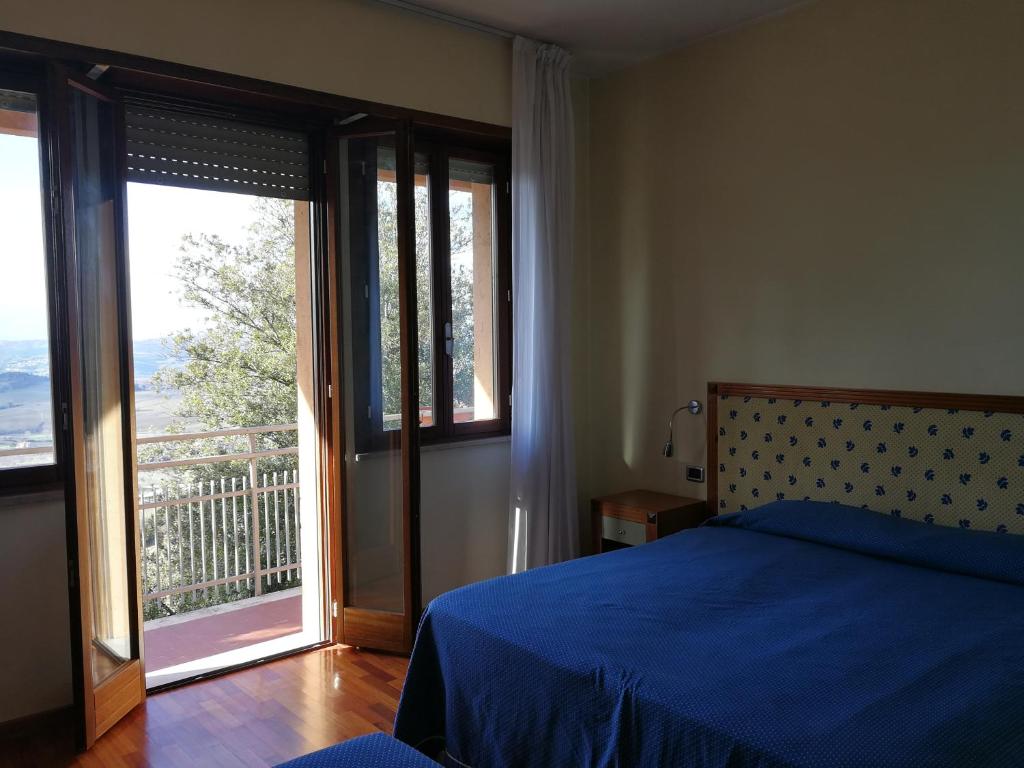 a bedroom with a blue bed and a large window at Hotel Il Castellaccio in Piccione