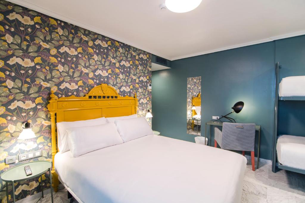 1 dormitorio con cama blanca y pared colorida en Petit Palace Puerta de Triana, en Sevilla