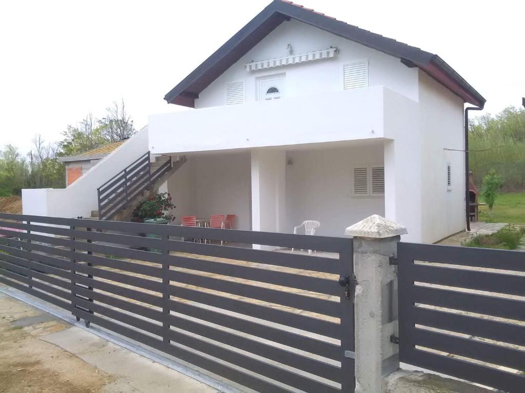 a white house with a black fence in front of it at Emilija Apartments Privlaka in Privlaka