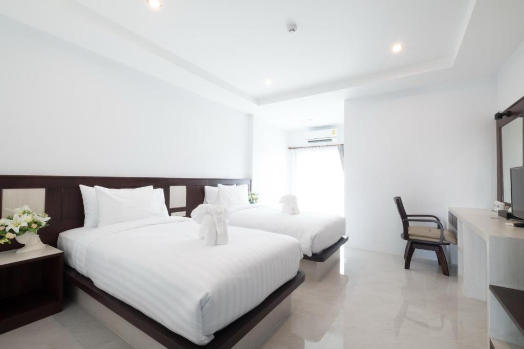 a bedroom with two beds and a tv and a desk at Sita Krabi Hotel in Krabi town