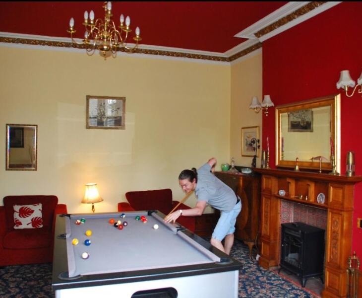 Denmore Guest House في أبردين: رجل يلعب البلياردو في غرفة المعيشة