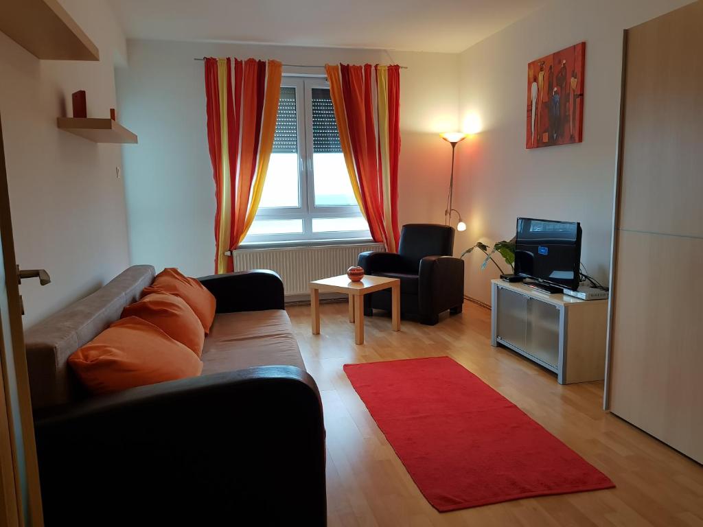 uma sala de estar com um sofá e uma televisão em Mészáros apartman em Bük