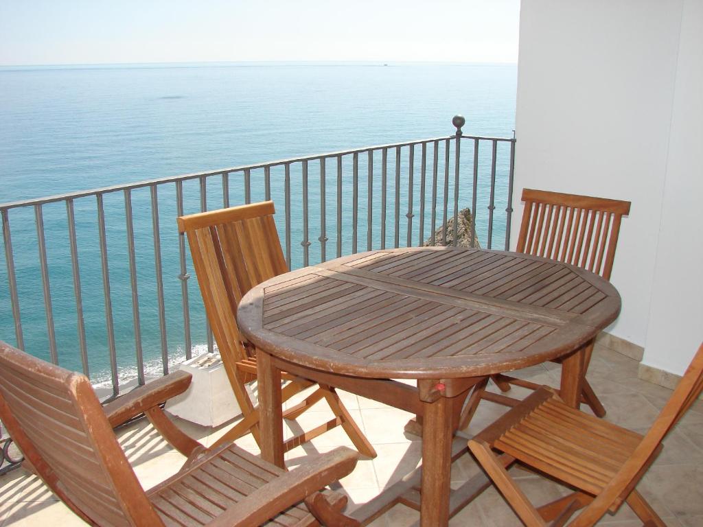 un tavolo in legno con sedie su un balcone con vista sull'oceano di CARABEO 70 MENYBER a Nerja