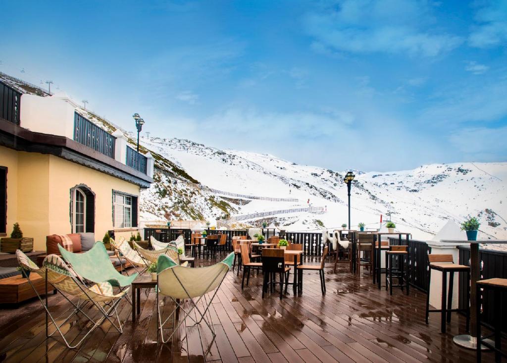 a patio with tables and chairs and snow covered mountains at Vincci Selección Rumaykiyya in Sierra Nevada