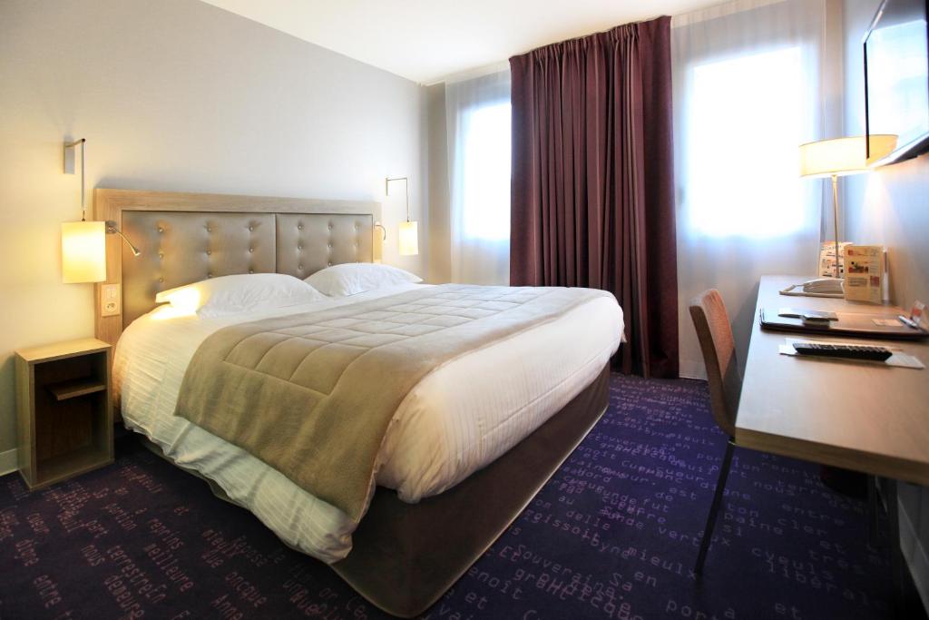 um quarto de hotel com uma cama grande e uma secretária em Hôtel Anne De Bretagne em Rennes
