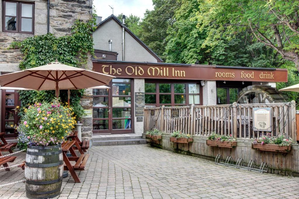 un restaurante con sombrilla frente a un edificio en The Old Mill Inn, en Pitlochry