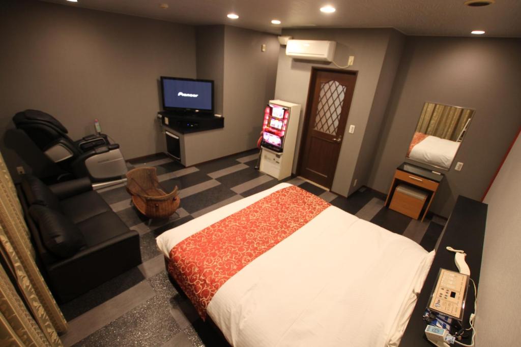 a bedroom with a bed and a tv and a couch at Hotel Sindbad Yamagata (Adult Only) in Higashine