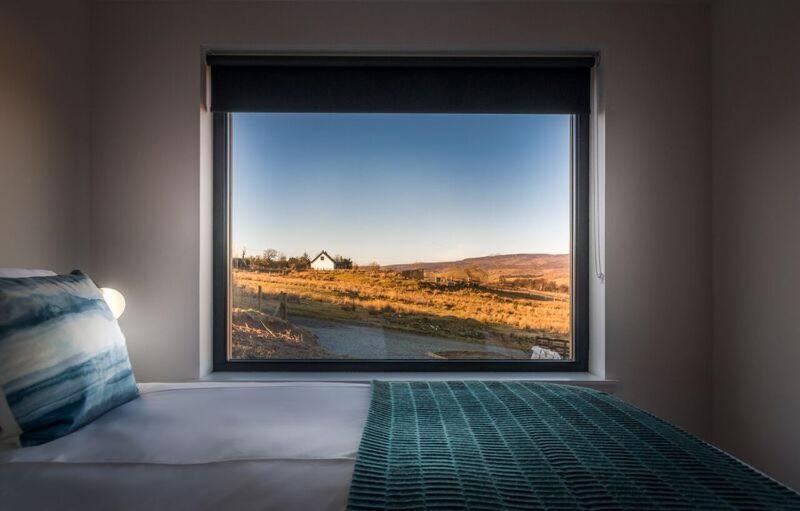 een slaapkamer met een groot raam met uitzicht op een veld bij Elfin Cottage in Portree