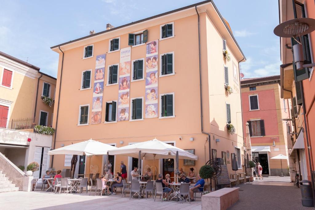 personas sentadas en mesas fuera de un edificio en Hotel Alla Torre en Garda