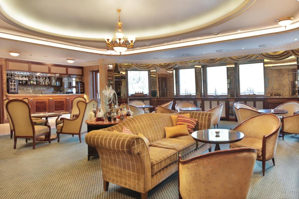 a living room with a couch and chairs and a bar at Retro Riverside Wellness Resort in Karlovy Vary