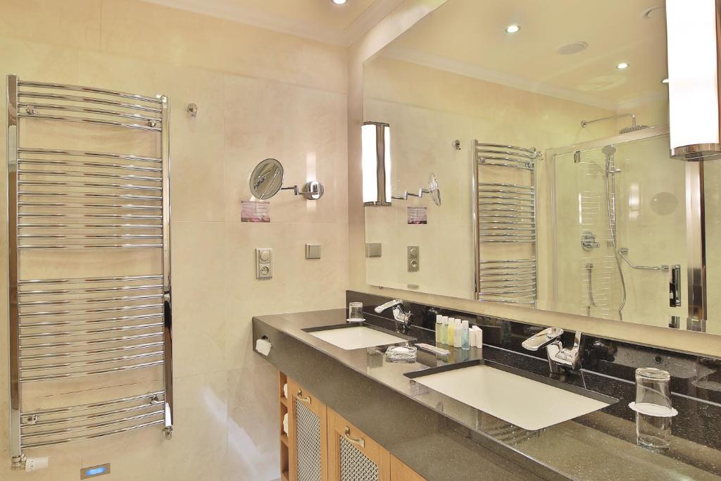 a bathroom with two sinks and a large mirror at Retro Riverside Wellness Resort in Karlovy Vary