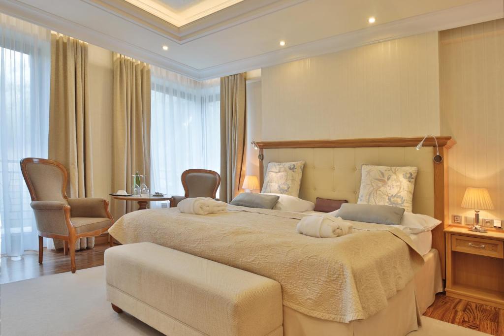 a large bedroom with a large bed and a chair at Retro Riverside Wellness Resort in Karlovy Vary