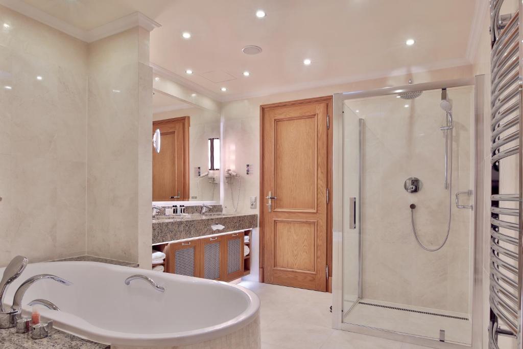 a bathroom with a bath tub and a shower at Retro Riverside Wellness Resort in Karlovy Vary