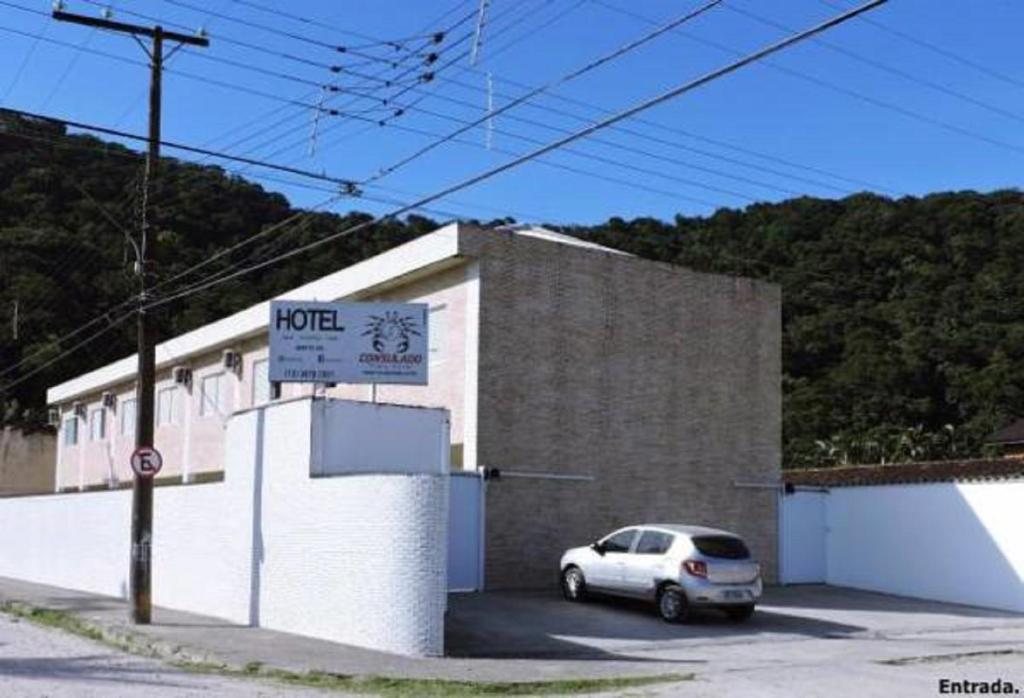 um carro branco estacionado em frente a um edifício em Consulado Praia Hotel no Guarujá