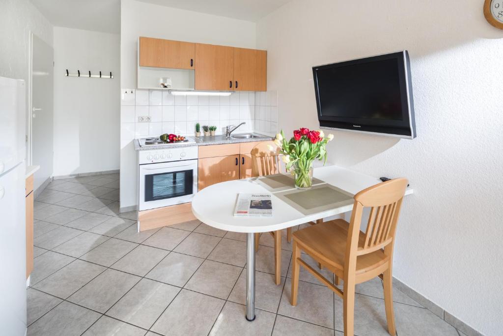 eine Küche mit einem weißen Tisch und Stühlen sowie einem TV in der Unterkunft Birkenhof in Norderney