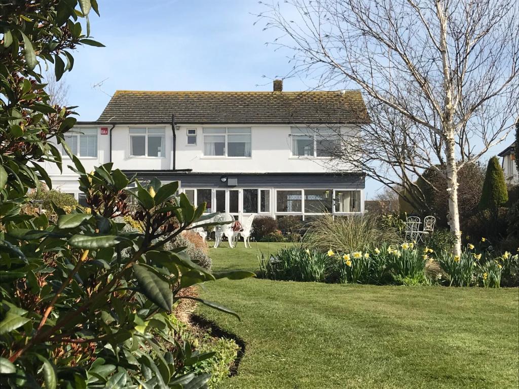 a white house with a yard with a dog at The Coast Yard B & B and Garden Chalets in Selsey