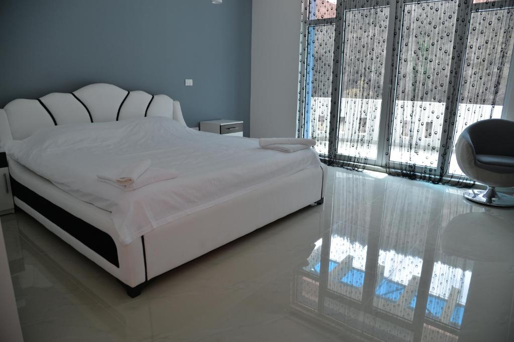 a bedroom with a white bed and a chair at B&B Hisar International in Prijepolje
