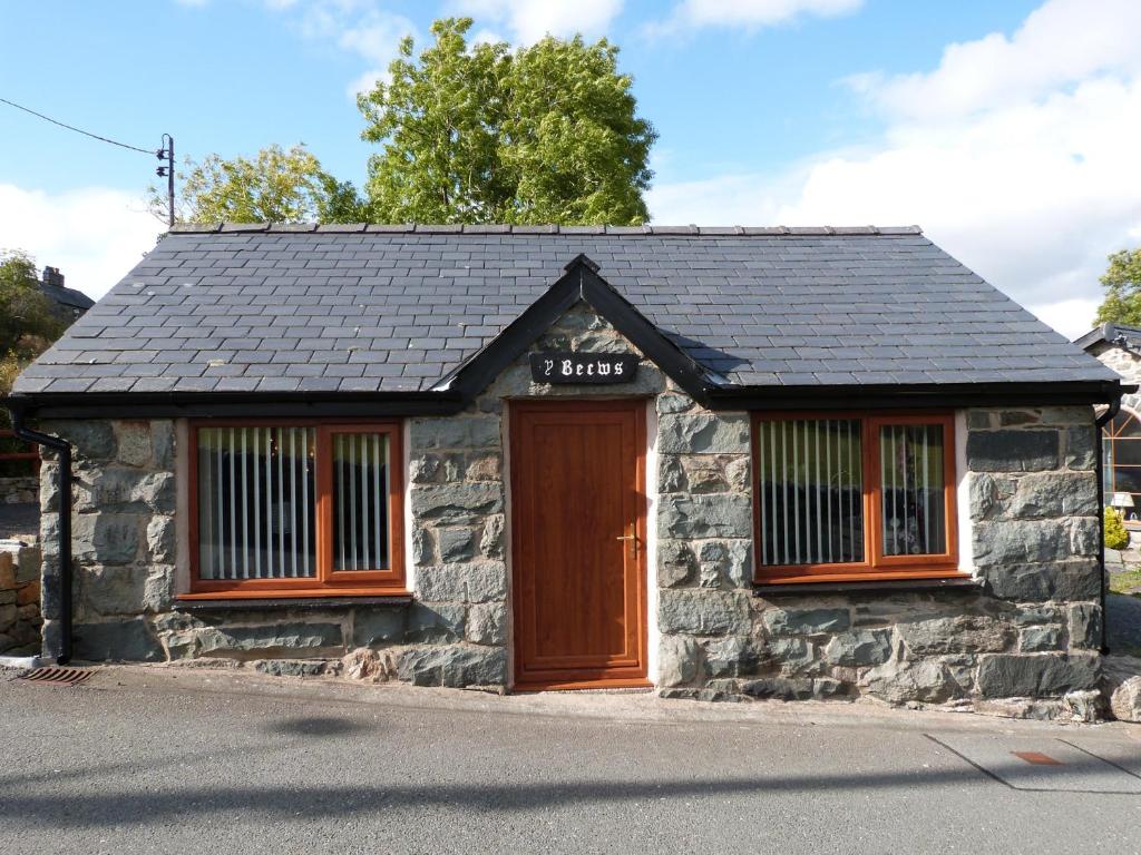 a small stone building with a brown door at Becws Clyd in Trawsfynydd