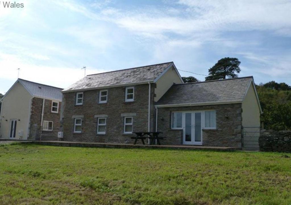 a large brick house with a grass field in front of it at Beudy Tawe in Pontardawe