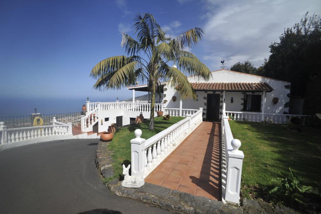 een huis met een wit hek en een palmboom bij Finca las Aguelillas in La Orotava