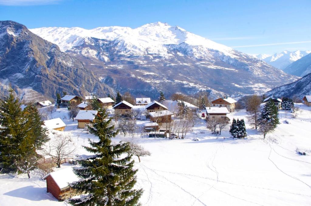 a village in the snow with a snow covered mountain at Les Sorbiers in Montricher-le-Bochet