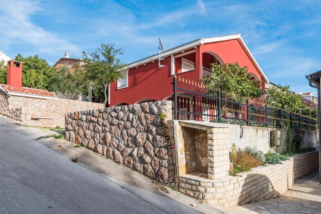 een rood huis met een stenen muur naast een straat bij House Danica in Obrovac