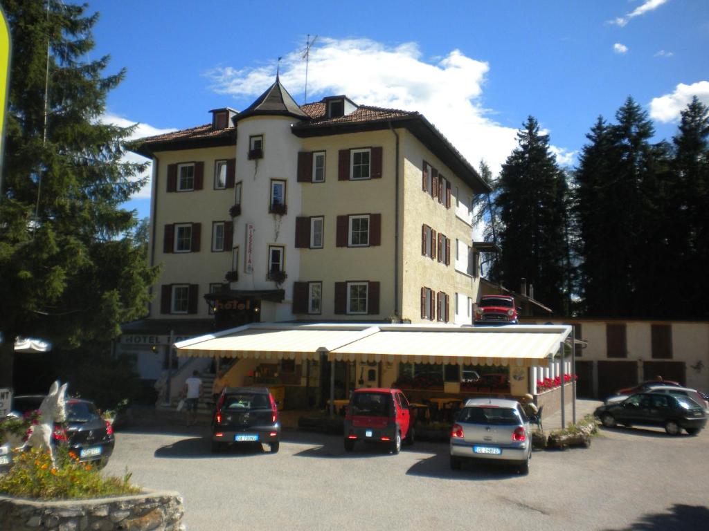 een groot gebouw met auto's geparkeerd op een parkeerplaats bij Hotel Roen Ruffrè-Mendola in Mendola